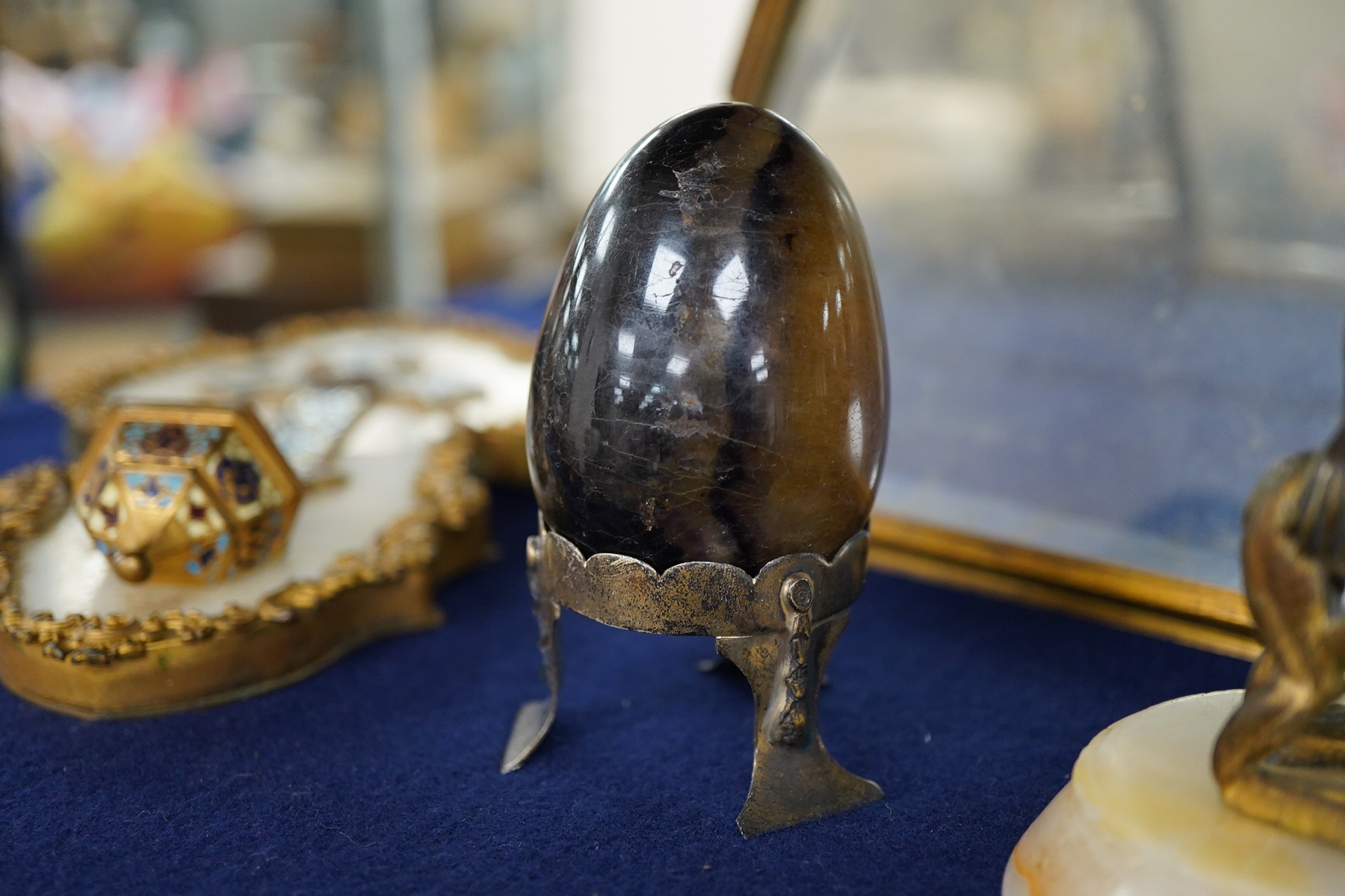 A Blue John egg, on white metal stand, an ormolu and alabaster candlestick cast as frogs, 18cm high, a French champleve, ormolu and alabaster holy water stoup and a gilt brass easel-back photograph frame